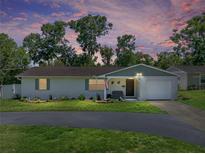 Charming single-story home featuring a well-manicured lawn and freshly painted white exterior with beautiful landscape at 37153 Mcminn Ave, Dade City, FL 33525
