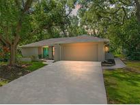 Charming single-story home with lush trees, a large driveway, and a bright blue double-door entryway at 39 Bishop Creek Dr, Safety Harbor, FL 34695