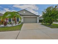 Charming home featuring a well-manicured lawn with a palm tree and a two-car garage at 4485 Eternal Prince Dr, Sun City Center, FL 33573