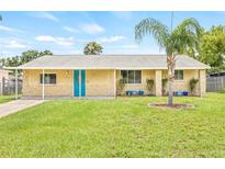 Charming single-story home with a well-manicured lawn and a vibrant blue front door, enhanced by a decorative palm tree at 6012 Flora Ter, Apollo Beach, FL 33572