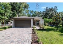 Charming single-story home featuring a brick driveway, a well-kept lawn and a two-car garage at 604 Kinnear Dr, Brooksville, FL 34601