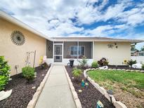 Charming front yard with a landscaped walkway leading to a screened-in porch under a cloudy sky at 8110 Damara Dr, New Port Richey, FL 34653