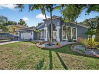 Charming home showcasing the landscaped front yard with beautiful columns and a two-car garage at 9220 Hidden Water Cir, Riverview, FL 33578