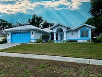 Charming one-story home with white exterior, blue trim, well-manicured lawn, and blue garage door at 1039 Greenturf Rd, Spring Hill, FL 34608