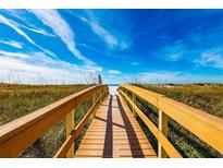 Wooden boardwalk leads to a white sandy beach under a bright blue sky at 12000 Gulf Blvd # 506N, Treasure Island, FL 33706