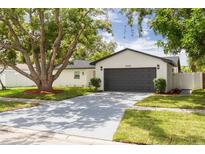 Charming single-story home featuring a large shade tree, a grey garage door, and a manicured front lawn at 12092 97Th Ave, Seminole, FL 33772