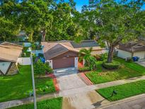 Well-maintained single-Gathering home featuring a lush, landscaped front yard and a two-car garage at 1242 Whisper Dr, Largo, FL 33770
