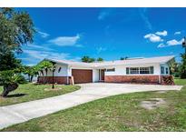 Inviting single-story home featuring a brick and stucco exterior, well-manicured lawn, and a curved driveway at 13883 Jamaica Dr, Seminole, FL 33776