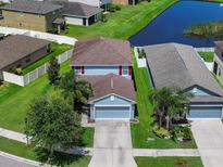 Two-story home featuring an attached garage, lush green lawn and a serene pond view at 1821 Hawks View Dr, Ruskin, FL 33570