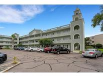 Low angle shows the building's facade, three stories, arched entryway, decorated railings, and parking lot in front at 2256 Philippine Dr # 24, Clearwater, FL 33763