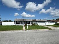 Modest single-story home featuring a front yard, driveway, and attached garage at 2619 Albion St, Holiday, FL 34691
