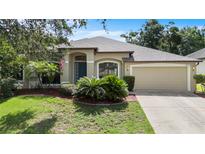 Beautifully landscaped one story home with a manicured lawn and attached two car garage at 8836 Alafia Cove Dr, Riverview, FL 33569