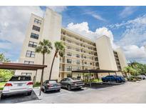 Multi-story condo building with covered parking, mature palm trees, and blue skies at 900 Cove Cay Dr # 1B, Clearwater, FL 33760