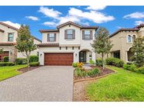 Charming two-story home showcasing a paved driveway, complemented by a well-manicured lawn and a garden area at 13299 Wildgrass Trl, Odessa, FL 33556