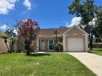 Charming single-story home with a well-maintained lawn, blooming tree and driveway leading to an attached one car garage at 1621 Crossridge Dr, Brandon, FL 33510