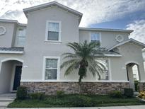 Charming townhome featuring a stone facade, a well-manicured lawn, and a beautiful palm tree at 1941 Greenwood Valley Dr, Plant City, FL 33563