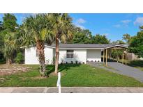Charming single-story home with white exterior, green lawn, and tropical palm trees at 485 Stillwater Ave, Spring Hill, FL 34606