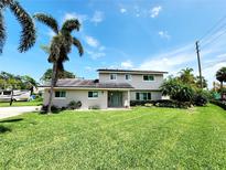 Charming two-story home with lush lawn, palm trees and a lovely blue sky at 5101 Dover Ne St, St Petersburg, FL 33703