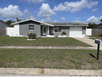 Charming single-story home featuring a manicured lawn and attached garage and mature landscaping at 1144 Rushmore Dr, Holiday, FL 34690