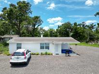 Charming single-story home with a gravel driveway and mature trees at 11907 Frontage Rd, Dade City, FL 33525