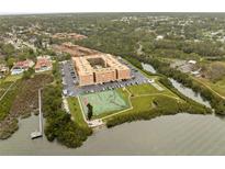 Scenic aerial view of waterfront condo community with tennis courts, a pier and lush greenery at 12760 Indian Rocks Rd # 1049, Largo, FL 33774