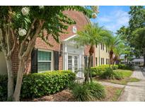 Brick building exterior featuring a white entrance and well-maintained landscaping with palm trees at 13684 Orange Sunset Dr # 101, Tampa, FL 33618