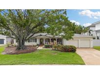 Charming single-story home with a well-manicured lawn, mature tree, and two-car garage at 3108 S Omar Ave, Tampa, FL 33629