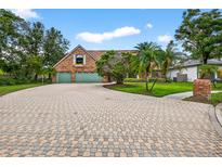 Charming brick home featuring a paved driveway, lush lawn, and mature trees under a sunny sky at 3269 Nicks Pl, Clearwater, FL 33761