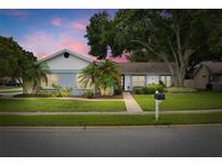 Charming single-story home with well-manicured lawn, mature trees and landscaping with a brick walkway leading to the front door at 3501 Sarazen Dr, New Port Richey, FL 34655