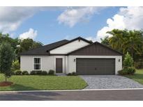 Charming single-story home with a well-manicured lawn and an attached two-car garage, under a cloudy blue sky at 36915 Sagemoor Dr, Zephyrhills, FL 33541