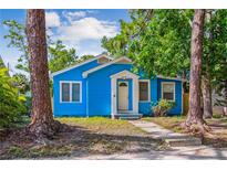 Bright blue bungalow with white trim, complemented by mature trees and a welcoming front porch at 4411 3Rd S Ave, St Petersburg, FL 33711
