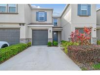 Charming townhome featuring a well-maintained lawn, a one-car garage, and stylish gray and blue accents at 6825 Citrus Creek Ln, Tampa, FL 33625
