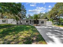 Charming single-story home boasts a manicured lawn and an inviting driveway, enhanced by mature trees and landscaping at 7003 Yule Ln, Tampa, FL 33637