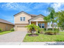Charming two-story home featuring a well-manicured lawn, beautiful landscaping, and a brick driveway at 11464 Chilly Water Ct, Riverview, FL 33569