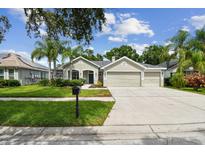 Charming single-story home with a well-manicured lawn, lush landscaping, and a three-car garage at 15217 Octavia Ln, Odessa, FL 33556