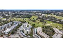 Expansive aerial view of a condo complex situated adjacent to a lush green golf course and serene lakes at 225 Country Club Dr # 1506, Largo, FL 33771