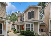 Charming two-story townhouse with tan siding, black shutters, covered entry, and landscaped front yard at 2377 Hounds Trl, Palm Harbor, FL 34683