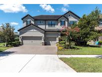 Stunning two-story home featuring a three-car garage, well-manicured landscaping, and a brick driveway at 3477 Barbour Trl, Odessa, FL 33556