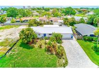 Beautiful single-story home featuring lush tropical landscaping, a metal roof and a paver driveway at 3928 E Eden Roc Cir, Tampa, FL 33634