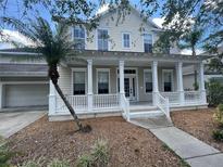 Charming two-story home featuring a welcoming front porch with white columns and a well-maintained front yard at 405 Islebay Dr, Apollo Beach, FL 33572