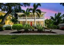 Charming two-story home with a red door, white trim, and a well-manicured lawn with tropical foliage at 4522 W Beachway Dr, Tampa, FL 33609