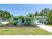 Charming, light-blue single Gathering home featuring lush landscaping, a well-manicured lawn, and a covered carport at 4718 24Th S Ave, St Petersburg, FL 33711