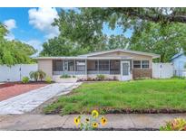 Charming home featuring well-manicured lawn, landscaped garden beds, and a screened-in porch at 4731 W Leila Ave, Tampa, FL 33616
