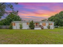 Charming single-story home featuring colorful accents, a cozy porch, and a sprawling front lawn at 5613 Forest Creek Rd, Lakeland, FL 33810