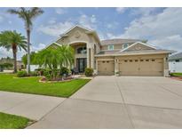 Inviting two-story home with a three-car garage, lush landscaping, and a grand entryway at 13728 Artesa Bell Dr, Riverview, FL 33579