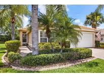 Charming single-story home featuring mature landscaping with palm trees, lush green lawn and a tile roof at 15744 Crystal Waters Dr, Wimauma, FL 33598