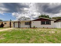 Charming home featuring white exterior, brown trim, and a well-manicured lawn at 3025 Palamore Dr, Holiday, FL 34691