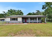 Charming single-story home features a covered porch, red front door and landscaped front yard at 3212 Cork Rd, Plant City, FL 33565