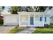 Charming home with a blue front door, white railing, and a walkway through the landscaped front yard at 3907 W Walnut St, Tampa, FL 33607