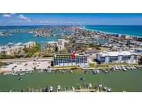 Stunning aerial view of a waterfront building with boat docks and a rooftop terrace at 400 150Th Ave # 504, Madeira Beach, FL 33708